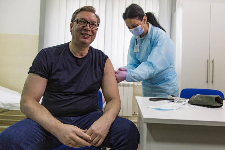 Aleksandar Vucic, sentado, sorri enquanto recebe uma dose de vacina contra a Covid-19