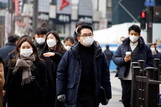 People wearing masks to prevent contracting the COVID-19 walk on a street in downtown Seoul