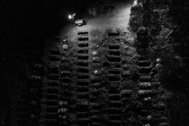 Vista aérea de quadra com covas abertas e holofotes para iluminar sepultamentos noturnos no Cemitério Vila Formosa, em São Paulo