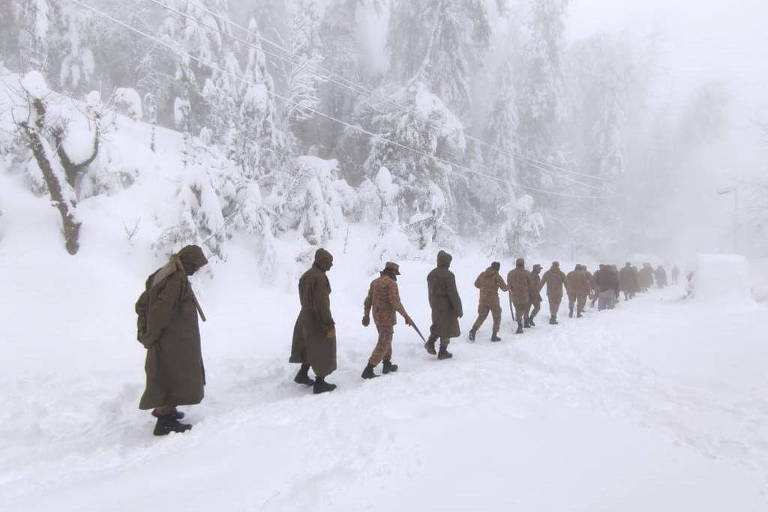 Soldados que fazem parte de equipes de resgate caminham na cidade de Murree sob tempestade de neve