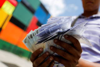 FILE PHOTO: The assistant of a bus driver holds 500,000 Bolivar banknotes, each worth just about 0.12 US Dollar, after Venezuela's central bank announced it will cut six zeros from prices, in Caracas