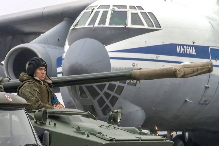 Soldado russo em blindado à frente de cargueiro Il-76 chega ao aeroporto de Almati, no Cazaquistão