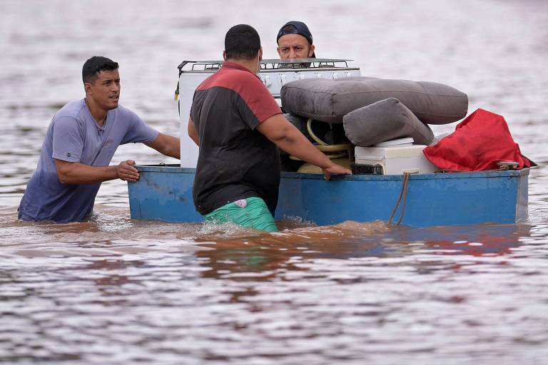 Homens carregam pertences após fortes chuvas na cidade de Juatuba, em Minas Gerais
