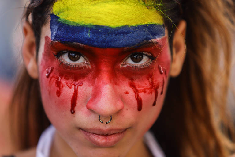 Uma ativista pinta o rosto com as cores da Colômbia em protesto em maio de 2021, em Bogotá