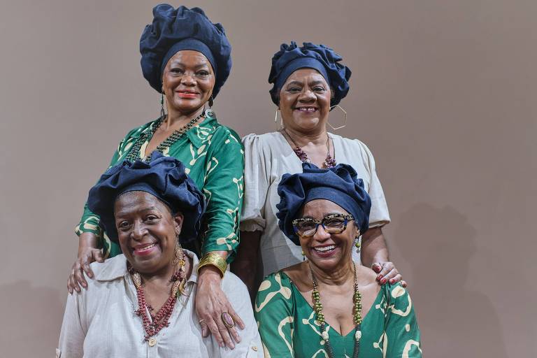 Em foto colorida, integrantes do quarteto Matriarcas do Samba posam para a câmera vestindo turbantes azuis e sorrindo