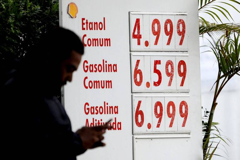Homem passa por um quadro exibindo os preços dos combustíveis em um posto de gasolina no centro de São Paulo, Brasil
