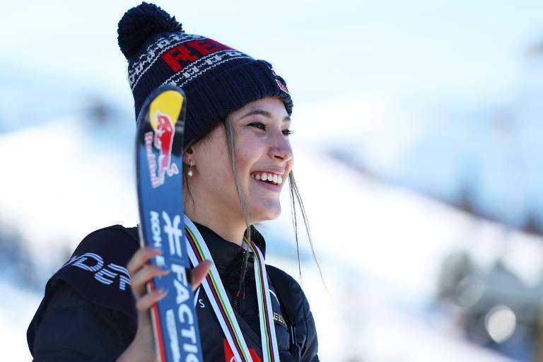 Esquiadora posa ao lado do esqui e sorrindo na neve