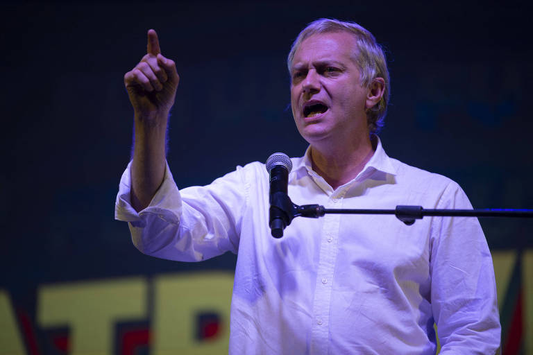 O ultradireitista José Antonio Kast, derrotado na eleição presidencial do Chile pelo esquerdista Gabriel Boric, durante discurso em Santiago antes do pleito; ele está atrás de um microfone, usa camisa social branca e exibe o dedo indicador da mão direita