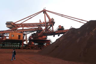 FILE PHOTO: Man walks by an iron ore blending site at Dalian Port