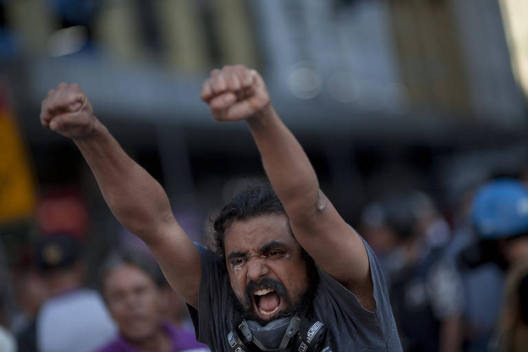 Manifestante com os punhos para o alto durante confronto com a polícia em protesto na Alerj