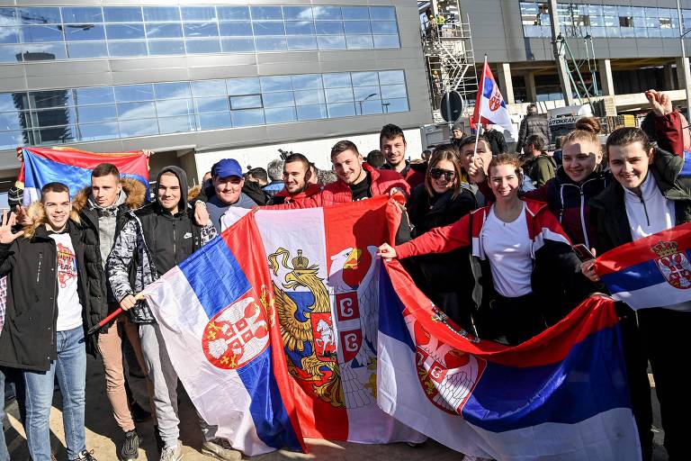 Jovens posam com bandeiras da Sérvia no aeroporto