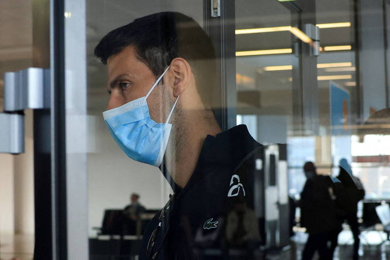 Djokovic de máscara atrás de vidro