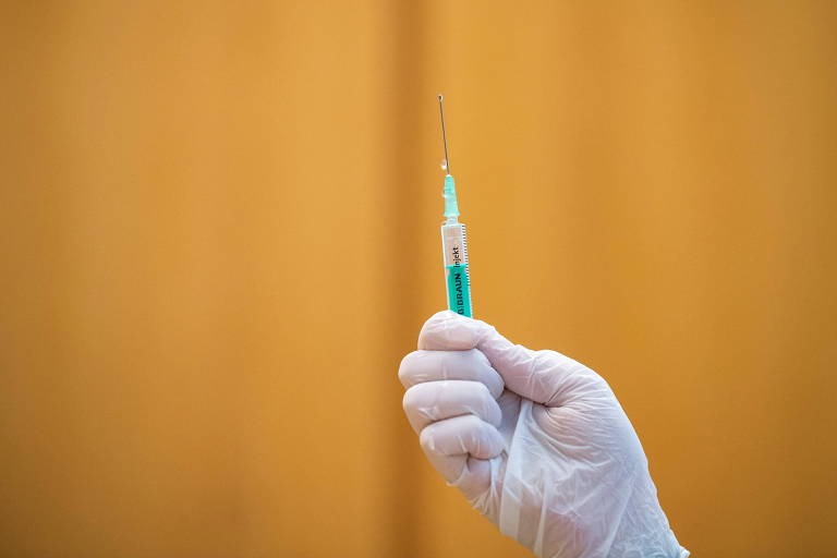 Mão com luva segura seringa com vacina pediátrica