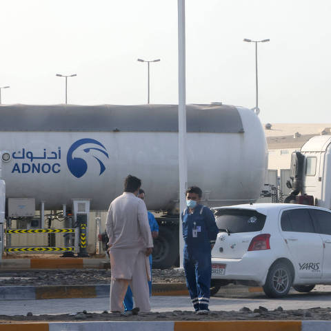 Men stand outside a storage facility of oil giant ADNOC in the capital of the United Arab Emirates, Abu Dhabi, on January 17, 2022. - Three people were killed in a suspected drone attack that set off a blast and a fire in Abu Dhabi today, officials said, as Yemen's rebels announced military operations in the United Arab Emirates. Two Indians and a Pakistani died as three petrol tanks exploded near the storage facility of oil giant ADNOC, while a fire ignited in a construction area at Abu Dhabi airport. (Photo by AFP)