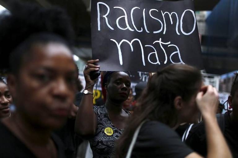 Manifestante segura placa onde se lê "racismo mata"