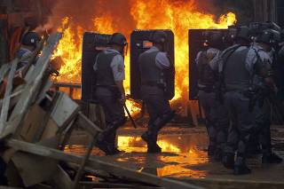 Police walk past a barrier set on fire by residents of the Pinheirinho slum who are resisting police arrival to evict them in Sao Jose dos Campos