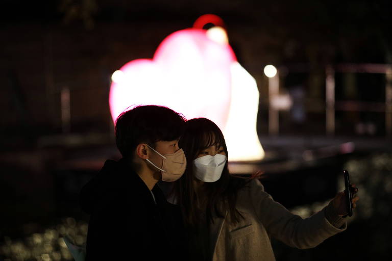 Casal com máscara de proteção posa para selfie em Seul, na Coreia do Sul