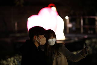 A couple wearing masks to avoid contracting the coronavirus disease (COVID-19) takes selfie in front of Heart-shaped lantern during the 2021 Seoul Lantern Festival in Seoul