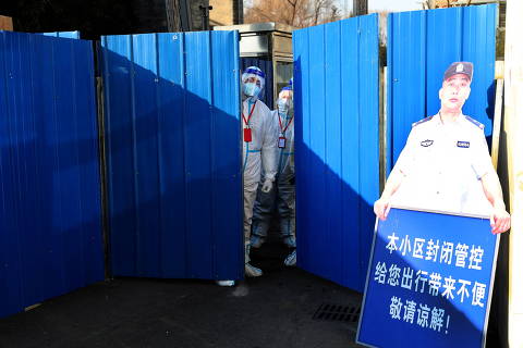 Workers wearing protective suits following the coronavirus disease (COVID-19) outbreak stand at an entrance to a residential compound under lockdown after a case of the Omicron variant was detected, in Beijing's Haidian district, China January 18, 2022. Picture taken January 18, 2022. China Daily via REUTERS  ATTENTION EDITORS - THIS IMAGE WAS PROVIDED BY A THIRD PARTY. CHINA OUT. ORG XMIT: PEK01