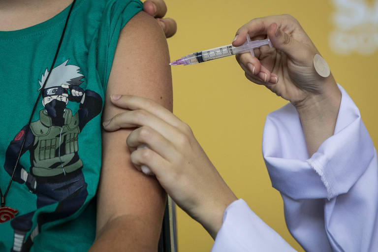 Imagem mostra o braço de um adolescente recebendo vacina