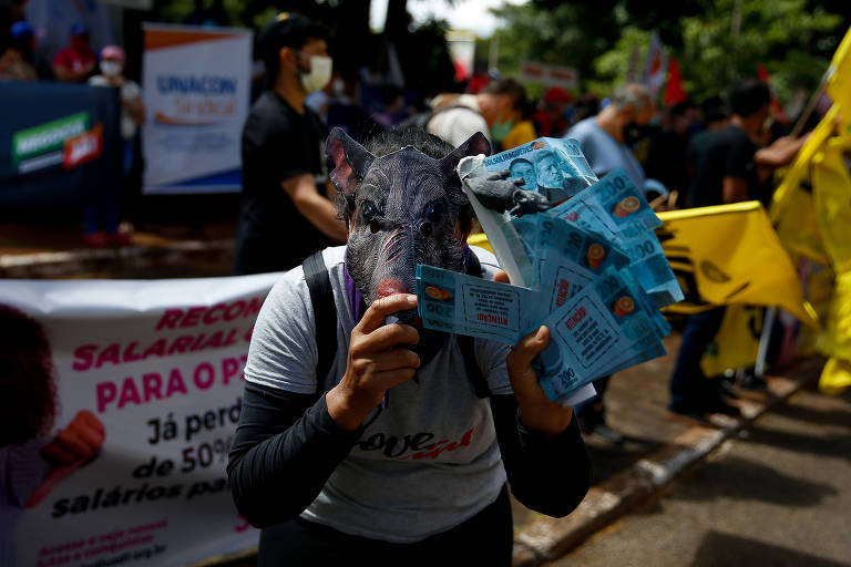 Bonecos retratando o ministro da Economia, Paulo Guedes, e notas de dinheiro com os rostos de Guedes, Bolsonaro e Arthur Lira são usados em ato de protesto 