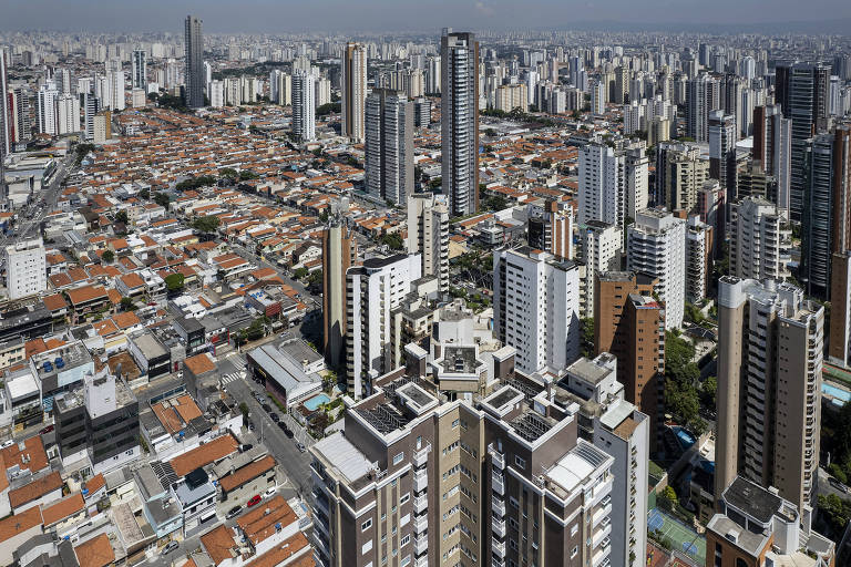 Imagem aérea mostra prédios e casas compondo uma paisagem urbana.