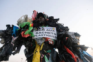 Modou Fall, who works to educate fellow Senegalase residents about the dangers of plastic trash, holds a sign reading Òno to plastic bagsÓ as he makes his case at the annual marathon in Dakar, Senegal, on Nov. 21, 2021. (Ricci Shryock/The New York Times)