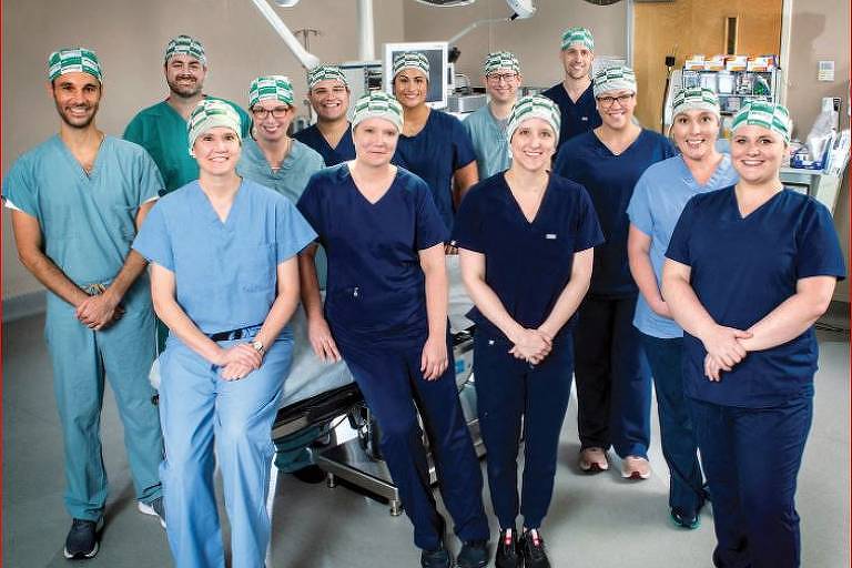 profissionais de saúde paramentados posam para foto em sala de cirurgia 
