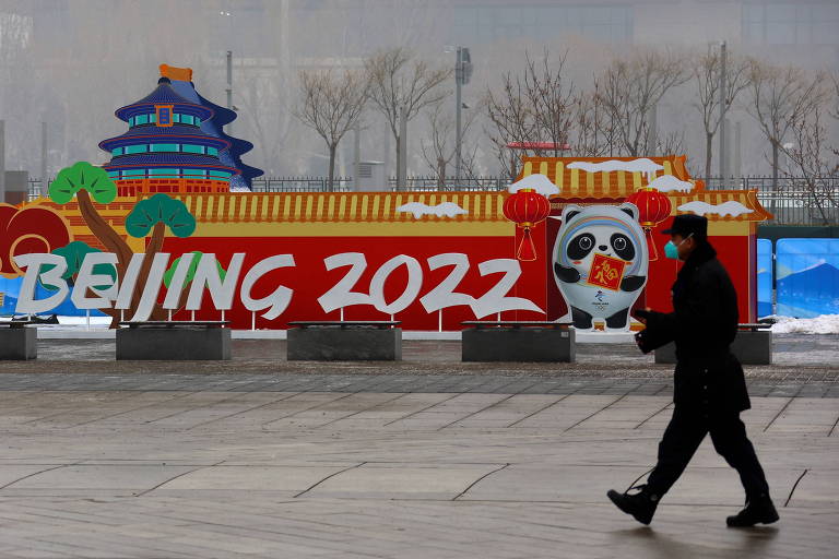 Guarda caminha em frente a uma placa publicitária dos Jogos de Inverno de Pequim