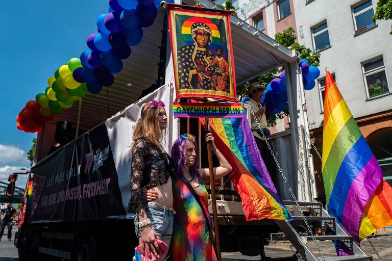 Manifestantes na parada LGBTQIA+ de Berlim carregam estandarte com arco-íris e motivos religiosos