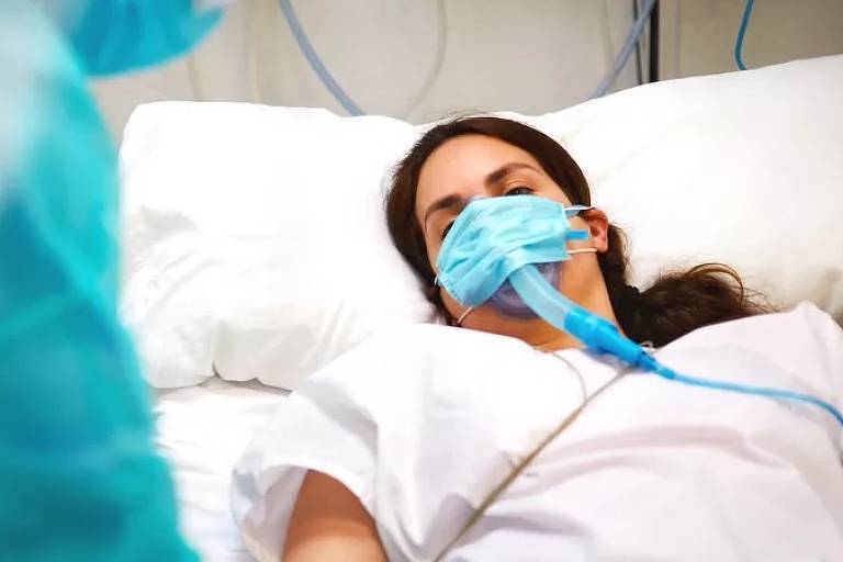 Imagem em primeiro plano mostra uma mulher intubada e deitada em uma maca de hospital