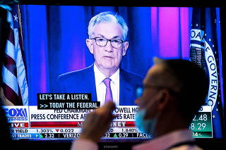 FILE PHOTO: A screen displays a statement by Federal Reserve Chair Jerome Powell following the U.S. Federal Reserve's announcement as a trader works on the trading floor of the NYSE in New York
