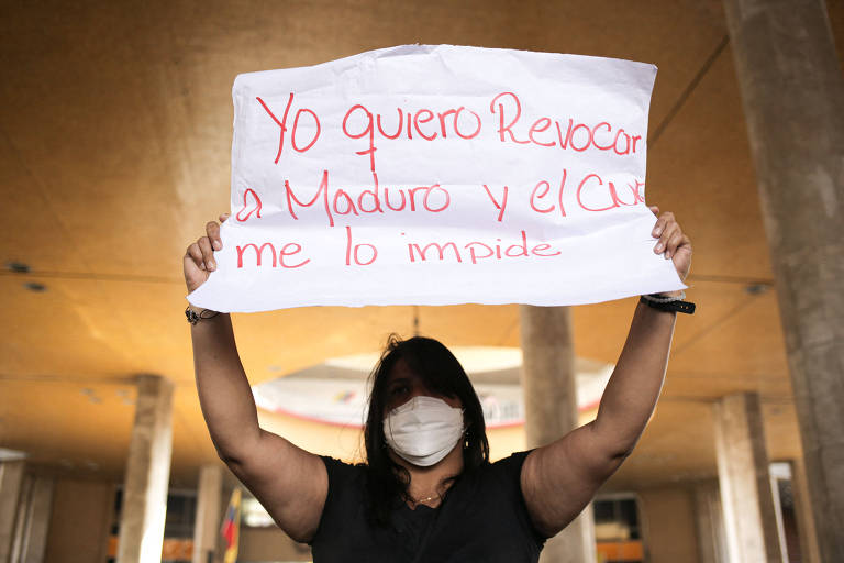 Manifestante segura cartaz com a frase 'quero tirar Maduro, mas o CNE me impede', em Caracas