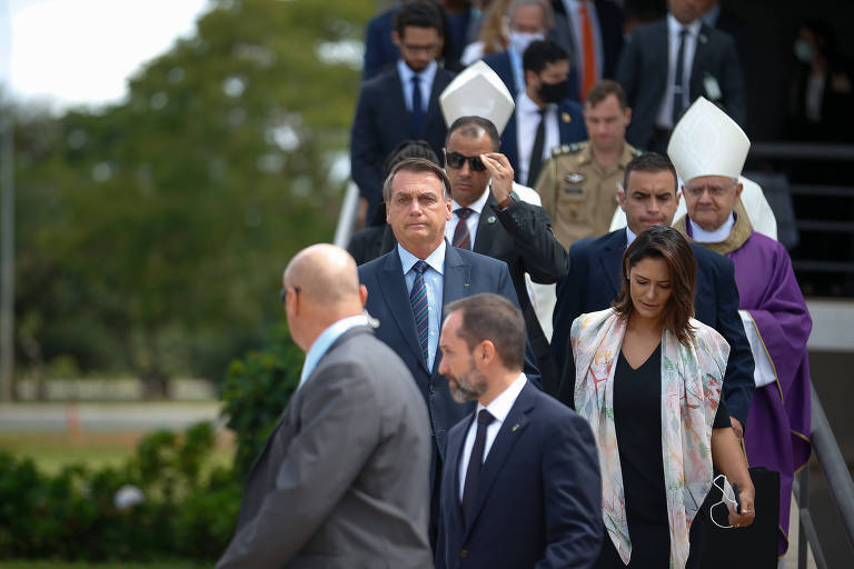 Descendo uma escala, Bolsonaro ao lado de Michelle. A frente deles, dois homens gbracos de terno. Atrás, bispos e outros homens de terno. Ninguém usa máscara
