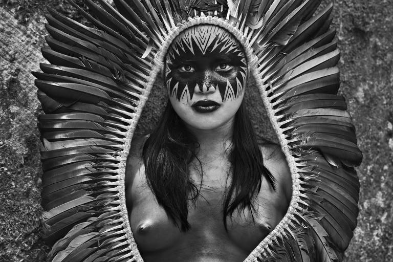 Indígena pintada e com cocar posa para retrato em preto e branco