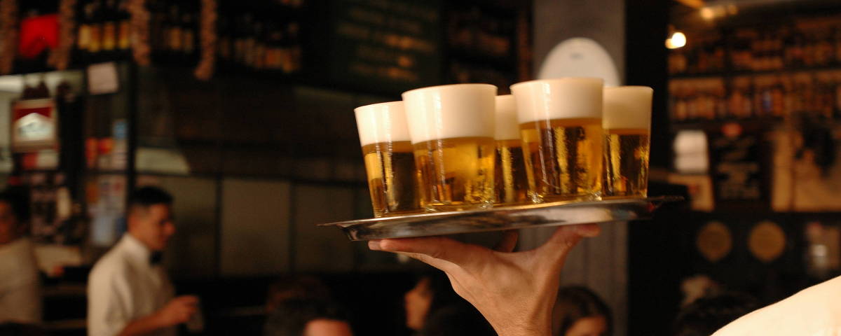 Garçom circula com copos de chope no salão do bar Filial, na Vila Madalena
