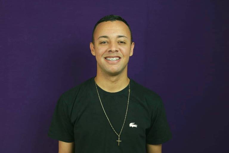 De pé, sorrindo e com camisa preta, o assistente de E-commerce Felipe Henrique, 21