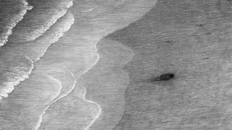bebê enrolado na praia em meio a ondas do mar em preto e branco