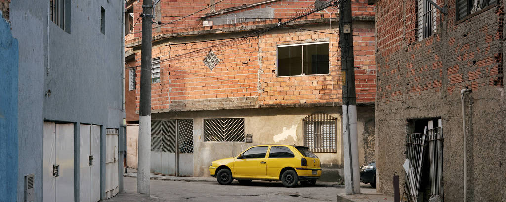 Rua com construções com tijolo exposto e um carro amarelo