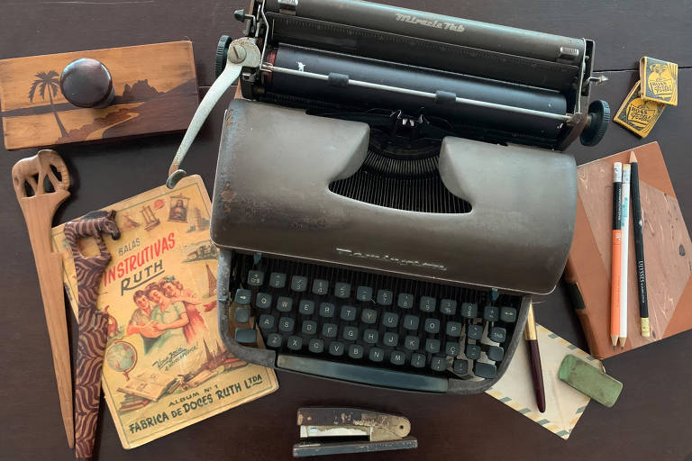 Alguns objetos de um escritório antigo, com máquina de escrever, grampeador, carimbo e outros objetos
