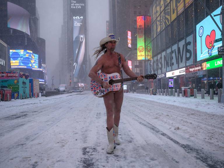 Um homem seminu tocando violão na Times Square, NY durante uma tempestade de neve