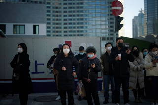 People wearing protective masks walk on a street, following new cases of COVID-19, in Shanghai