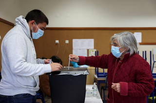 A woman wearing a protective face mask casts her ballot during Portugal's general election in Lisbon