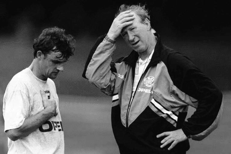 O inglês Jack Charlton, então técnico da seleção da Irlanda, leva a mão à cabeça durante treinamento do time em 1994; ao seu lado está, cabisbaixo, o jogador Kevin Moran