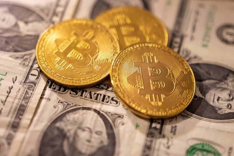 Moedas representando o Bitcoin dispostas acima de cédulas de dólares