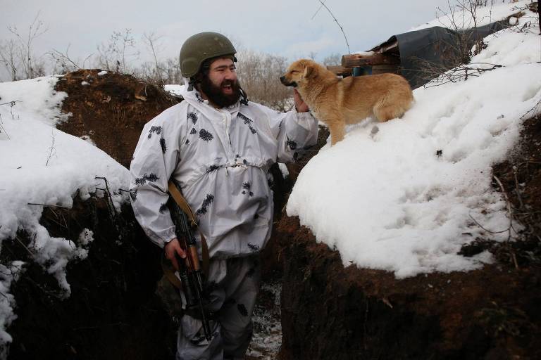 Soldado ucraniano brinca com cachorro em trincheira perto da linha de frente de Donetsk