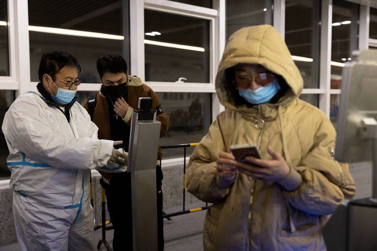 Funcionário confere informação sanitária de passageiros que chegam à estação Taizicheng, em Zhangjiakou, na China