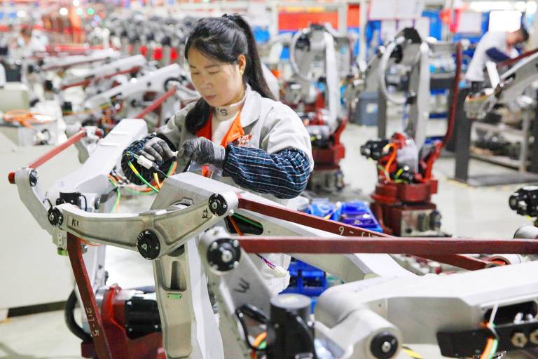 Trabalhadora verifica produtos em uma linha de montagem de robôs em província no leste da China
