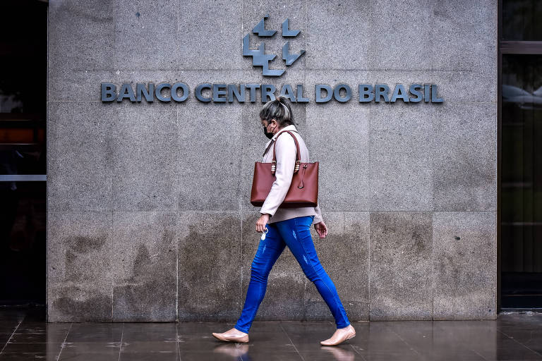 Mulher caminha em frente à fachada da sede do Banco Central do Brasil, em Brasília (DF)