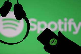 FILE PHOTO: A smartphone and a headset are seen in front of a screen projection of Spotify logo, in this picture illustration